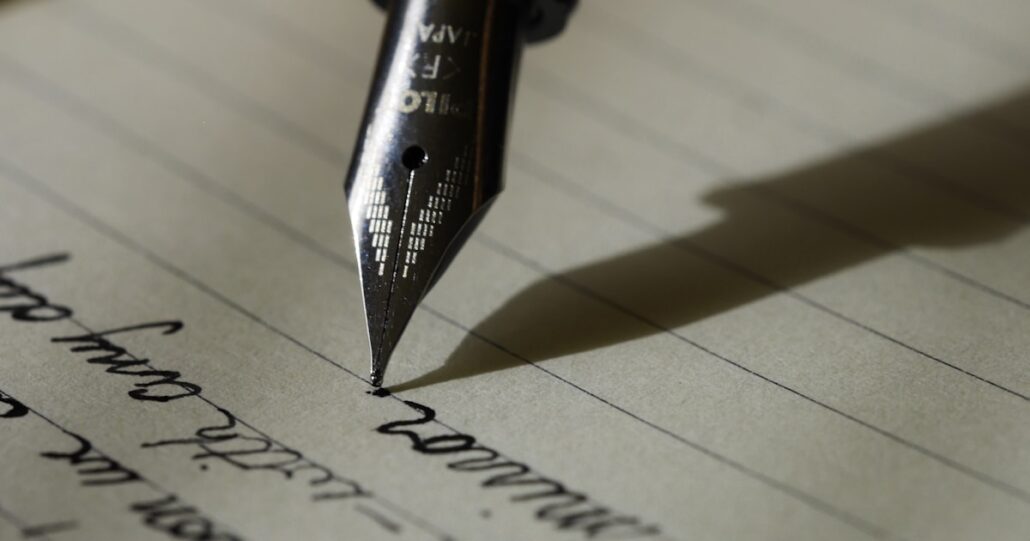 Person writing resume bullet points in notebook